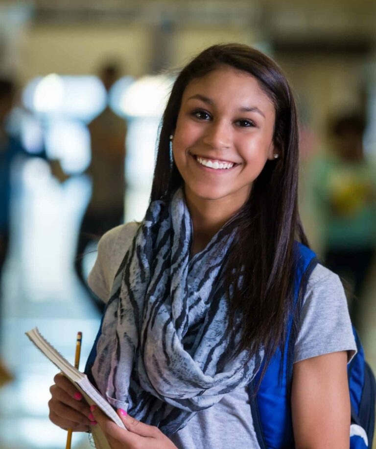 Happy mixed race teen girl in high school hallway
