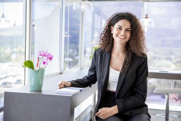 Young business leadership coach smiling at the camera while sitting in the office