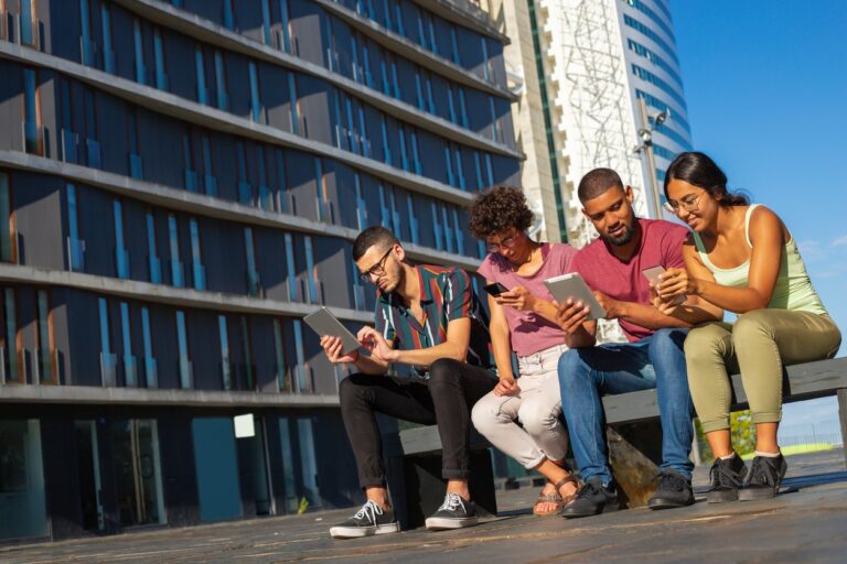 Group of friends sitting outside while being on social media