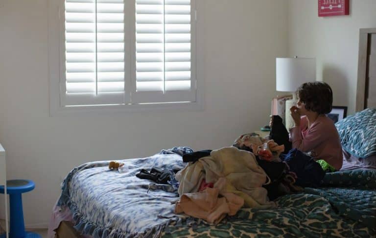 Young anxious child sitting on bed