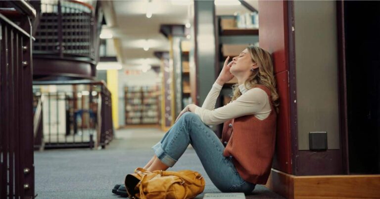 College student with bipolar disorder experiencing brain fog while sitting on the library floor.