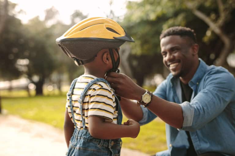 Father helping child with helmet to protect his head