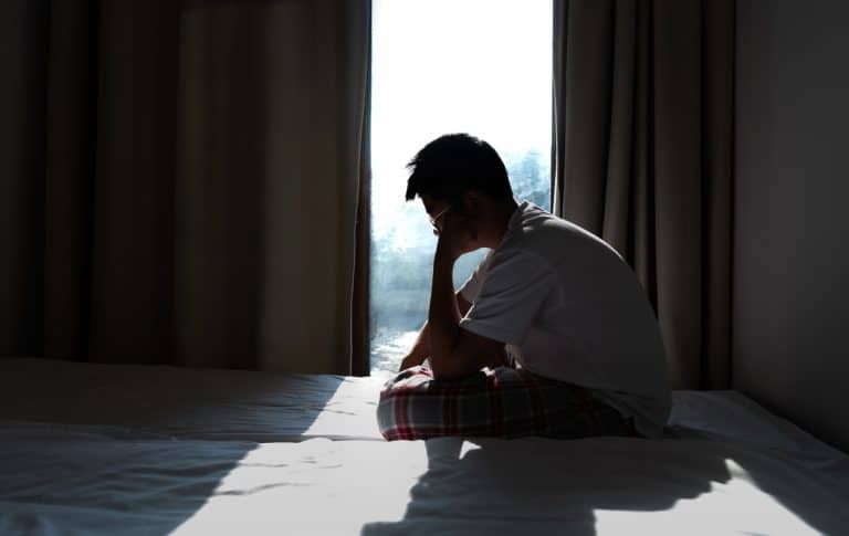 Teen sitting on their bed suffering with depression