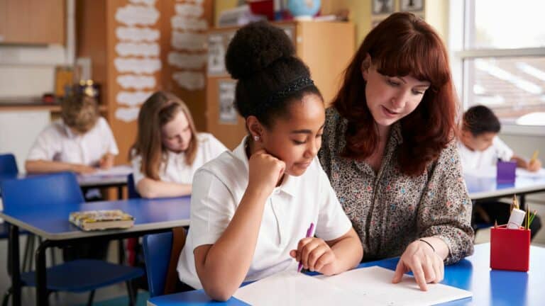 Teacher helping learner in classroom