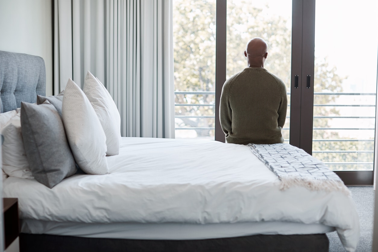 Rearview shot of a mature man looking through a window in a bedroom at home