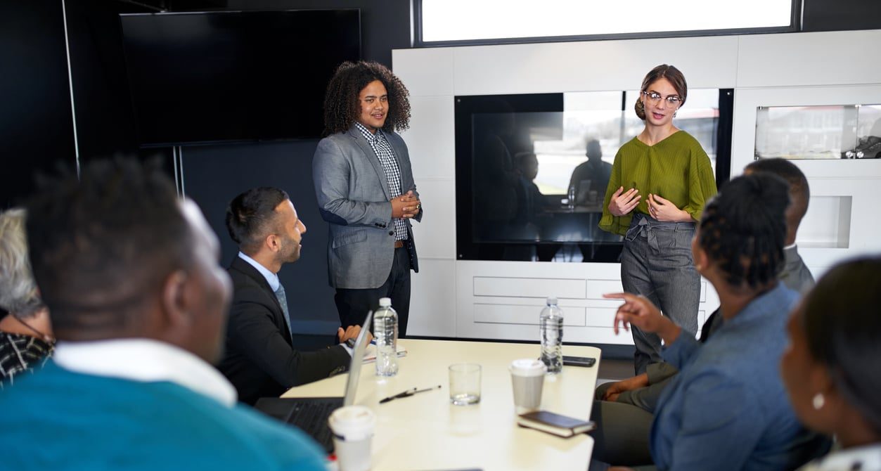 Multi-ethnic group of coworkers discussing in modern meeting room with female boss and laptop computer
