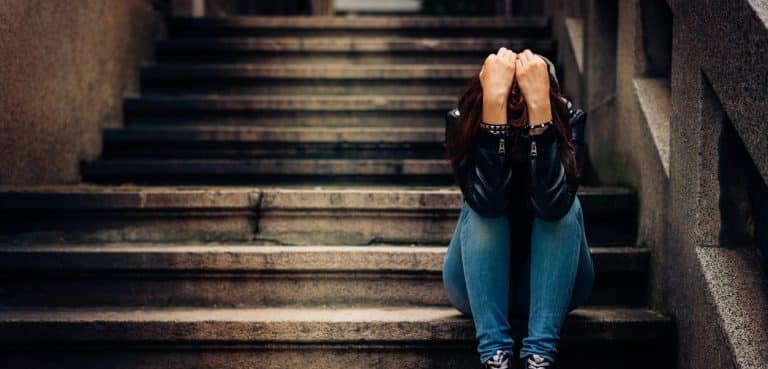Teen suffering with depression sitting on the stairs and thinking about suicide