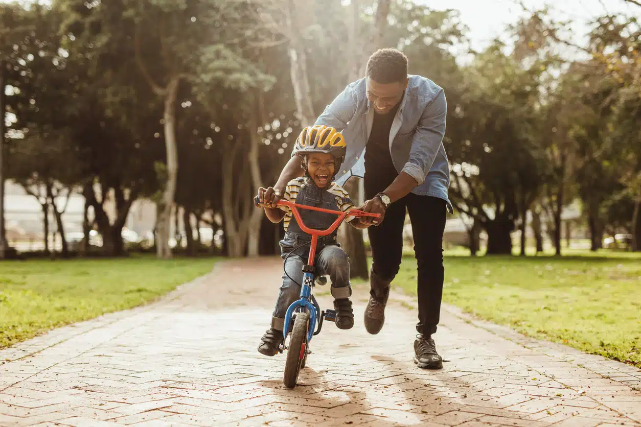 Father teaching his son cycling at park. Microsystem of the Ecological Systems Theory