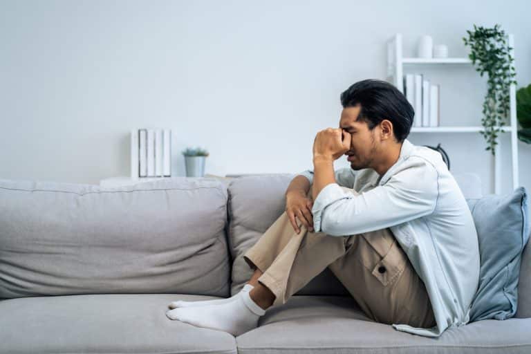 Young man with anxiety, sitting on the couch at home