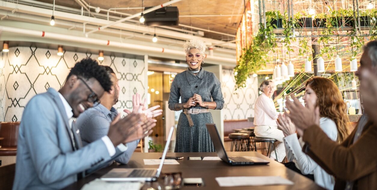 Business people applauding one another at a presentation in a skills-based organisation