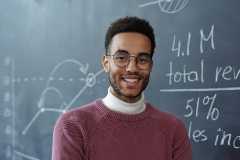 Young teacher who makes a difference standing in his classroom after completing a PGCE