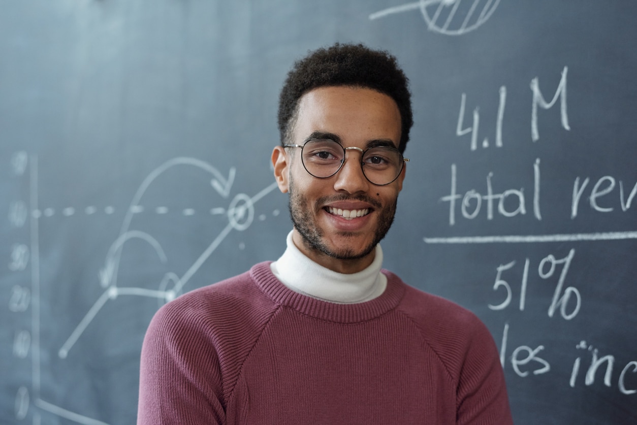 Young teacher who makes a difference standing in his classroom after completing a PGCE