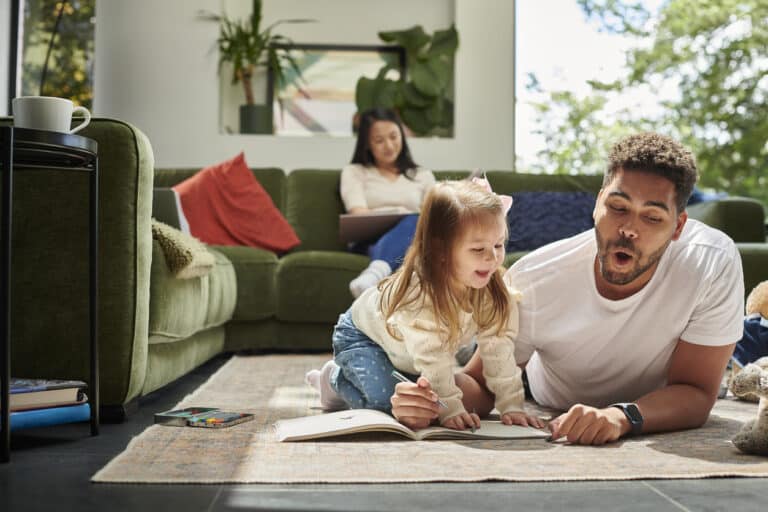 Dad and daughter laying in their home while exploring the benefits of reading as a family
