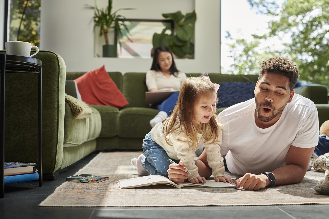 Dad and daughter laying in their home while exploring the benefits of reading as a family