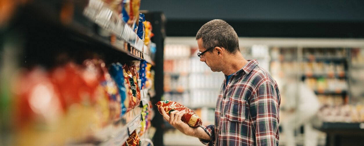 Man shopping and reading a marketing label on a product while deciding what to buy