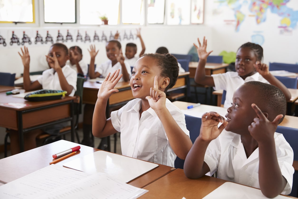 Learners in classroom with their hand up, eager and confident enough to answer questions