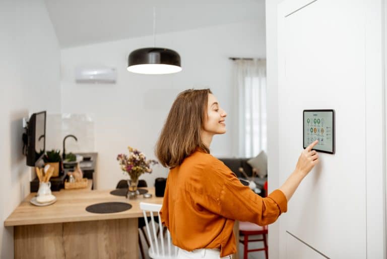 Woman standing at the control panel in her smart home that is powered by AI to create everyday processes