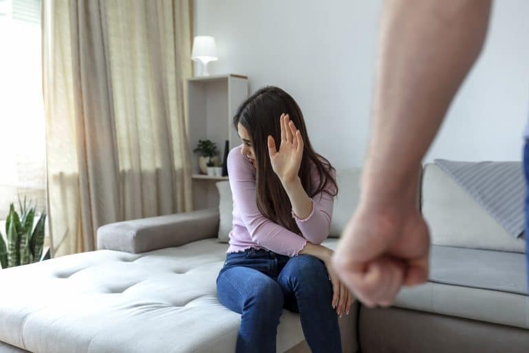 Cropped shot of a young woman trying to protect herself from a man's clenched fist.