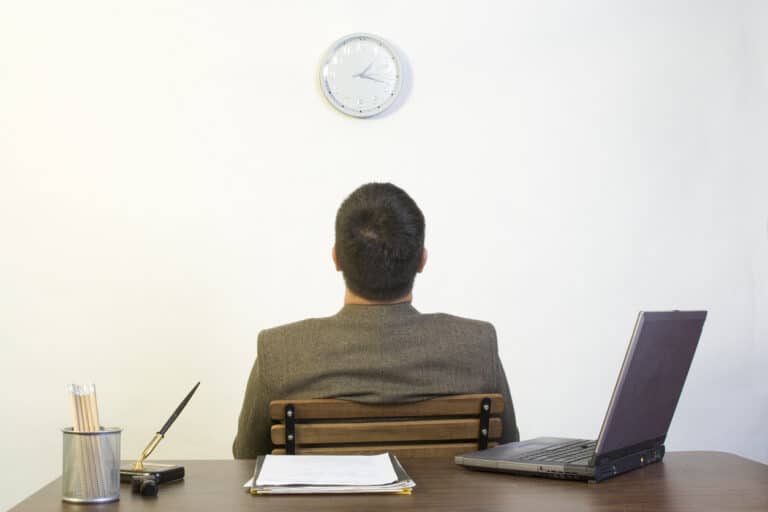 Man in his office, procrastinating and looking at the time