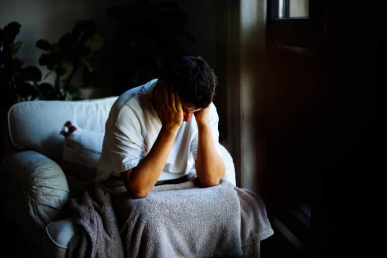 Man with depression sitting with his head in his hands and needs help