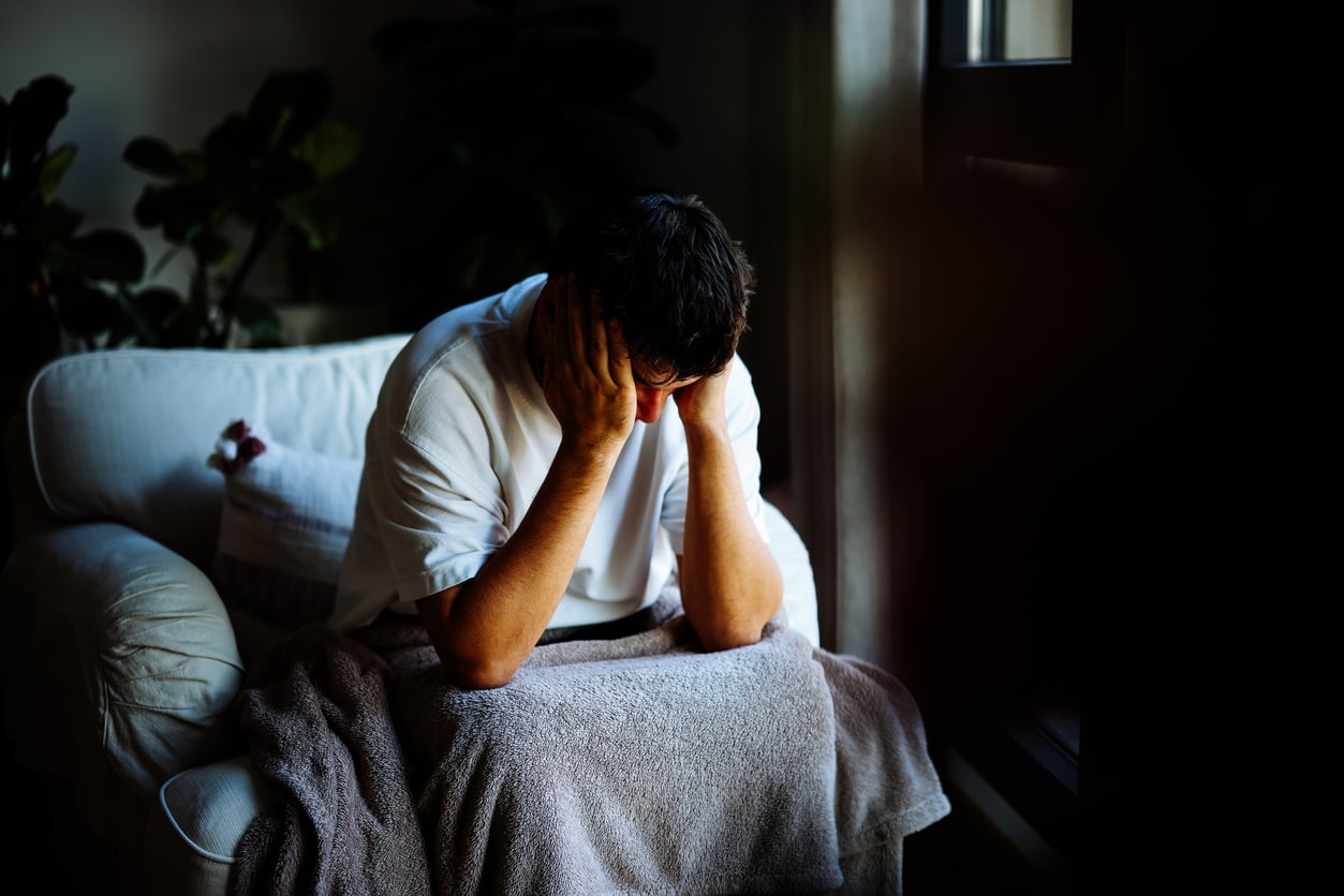 Man with depression sitting with his head in his hands and needs help