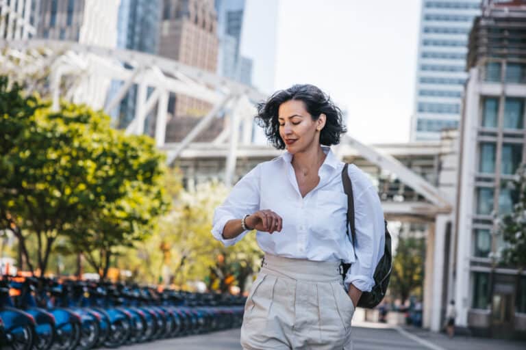 Businesswoman walking looking at the time because of procrastination.